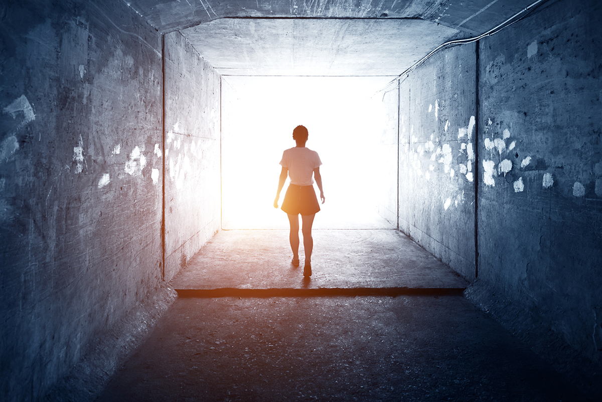 woman walking to light at the end of a tunnel